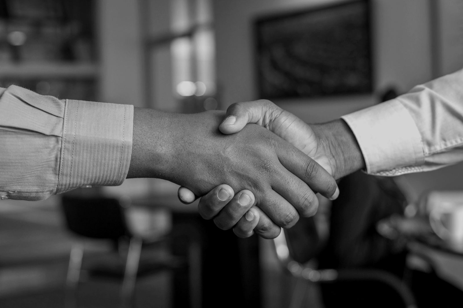 Two business partners shaking hands across a table